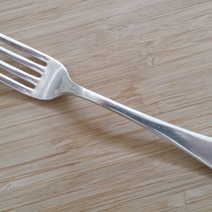 May include: A silver fork with a decorative handle. The handle has a floral design.