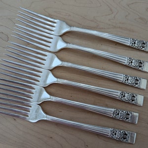 May include: Set of six silver forks with ornate handles. The forks have a traditional design with a decorative floral pattern.