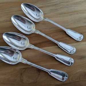 May include: Four silver spoons with ornate handles. The spoons are arranged in a row, with the handles pointing to the right.