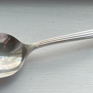 May include: A silver spoon with an ornate handle. The handle has a floral design and a raised crest.