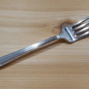 May include: A silver fork with an ornate handle. The handle has a floral design.