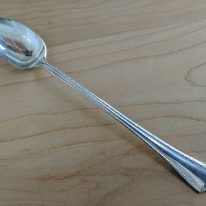 May include: A silver iced tea spoon with a decorative handle.