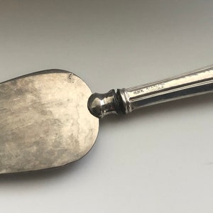 May include: Silver cheese knife with a hammered handle and a pointed blade.