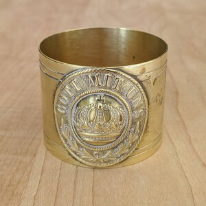 May include: A gold-colored metal ring with the inscription "Gott Mit Uns" and a crown design. The ring is a vintage style and has a worn finish.