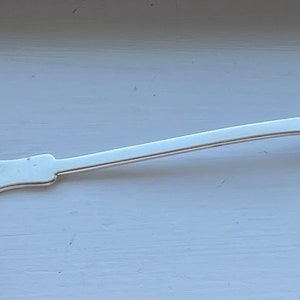 May include: A silver ladle with a long, slender handle. The bowl of the ladle is round and has a smooth, polished surface.