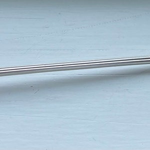 May include: A silver-plated cocktail fork with an ornate handle. The fork has three tines and a long, slender handle.