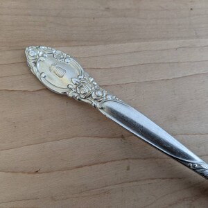 May include: Silverware with an ornate handle featuring a pineapple design and floral accents.