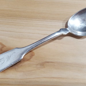Puede incluir: Una cucharita de plata con un cuenco redondeado y un mango simple y elegante. El mango está grabado con el número "925".