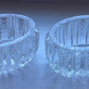 May include: Two clear glass bowls with intricate cut glass designs. The bowls are round and have a scalloped edge.