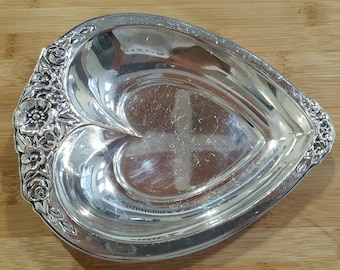 May include: A silver heart-shaped serving dish with a raised floral design around the edge.