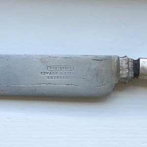 May include: A silver butter knife with a textured blade and a plain handle. The knife has the inscription "Wm. Rogers & Son" and "1847 Rogers Bros." on the blade.
