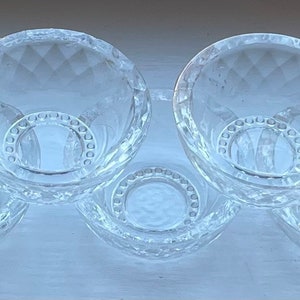 May include: A clear, five-section serving dish. Each bowl has a diamond-cut pattern and a circular base with a beaded design. The bowls are arranged in a curved line, perfect for serving snacks or condiments.