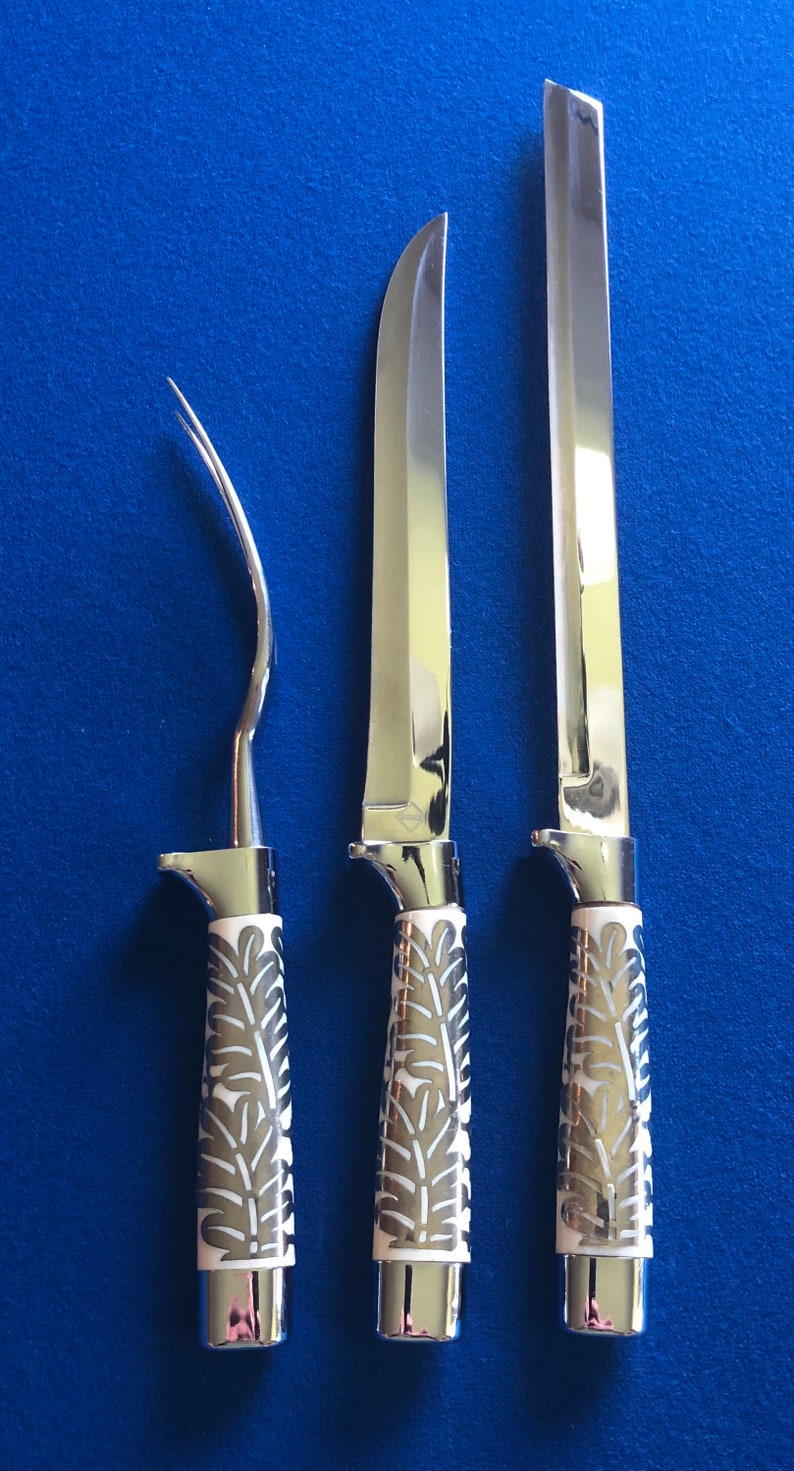 May include: Three silver knives with white handles featuring a floral design. The knives have different blade shapes and sizes.