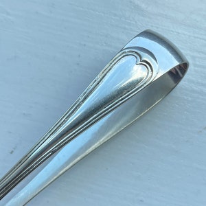 Puede incluir: Pinzas de azúcar de plata con un diseño en forma de corazón en la parte superior.