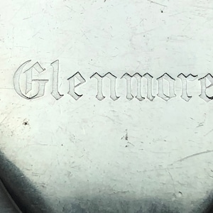 May include: Close-up of a silver spoon with the word "Glenmore" engraved in a gothic font.