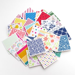 May include: A stack of colorful patterned paper cards with various designs, including polka dots, stripes, flowers, and geometric shapes.