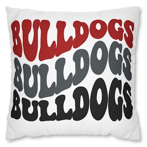 May include: White pillow with the word "Bulldogs" repeated three times in red, gray, and black lettering. The lettering is in a retro, wavy font.