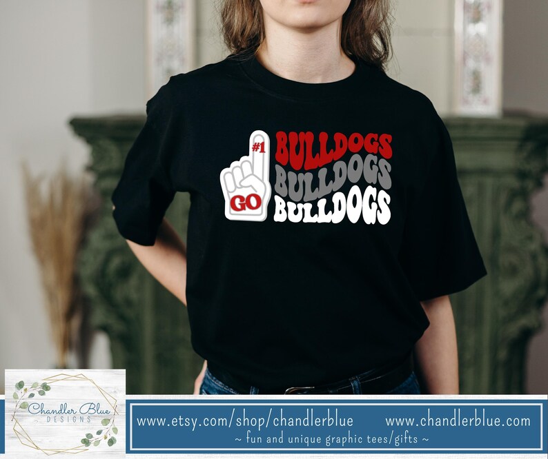 May include: Black t-shirt with a white graphic design that says "#1 BULLDOGS BULLDOGS BULLDOGS" with a red "GO" in a hand gesture.