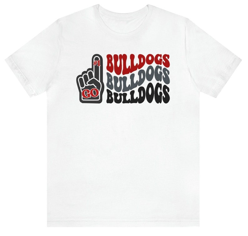 May include: White t-shirt with a red, gray, and black graphic design. The graphic features a raised fist with the number "#1" on the index finger and the words "GO BULLDOGS" repeated three times.