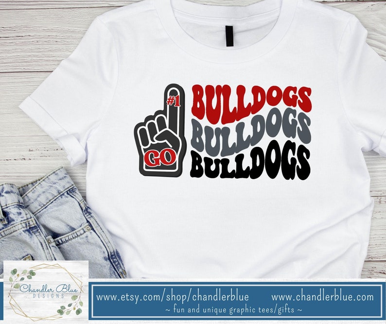 May include: White t-shirt with a red, gray, and black graphic design that says "#1 GO BULLDOGS BULLDOGS BULLDOGS".