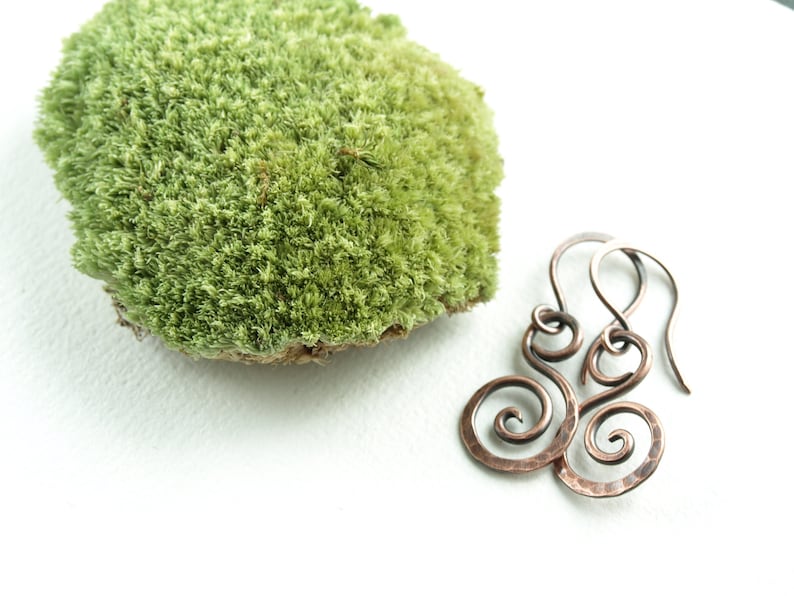 May include: A pair of copper wire earrings with a hammered finish. The earrings are shaped like a double spiral.