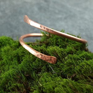 Può includere: Un braccialetto in rame martellato con un design semplice e minimalista. Il braccialetto è realizzato in un unico pezzo di rame che è stato piegato in un cerchio e poi martellato per creare una superficie testurizzata.