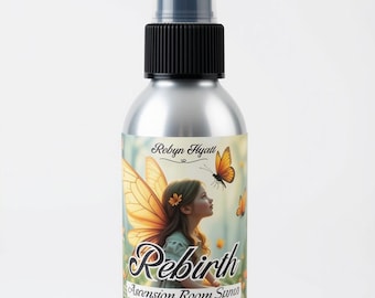 May include: A silver metal spray bottle with a black pump and clear cap. The label features a fairy illustration, the text Robyn Hyatt, Rebirth, Ascension Room Spray, Wild Sage, Orange, Myrrh, Frankincense, and the volume 4 oz.