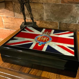 May include: A black wooden box with a Union Jack design on the lid. The box features a royal crest with the letters "E.R." in the center.