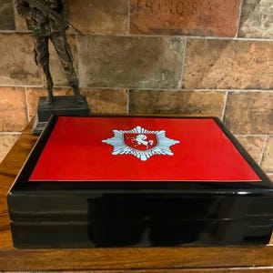 May include: A black wooden box with a red lid. The lid features a white emblem with a horse and the words "The White Horse Inn" on it.