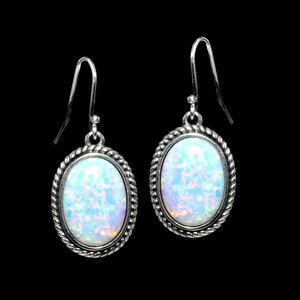 May include: A pair of silver earrings with oval-shaped white opal stones set in a rope-like design.