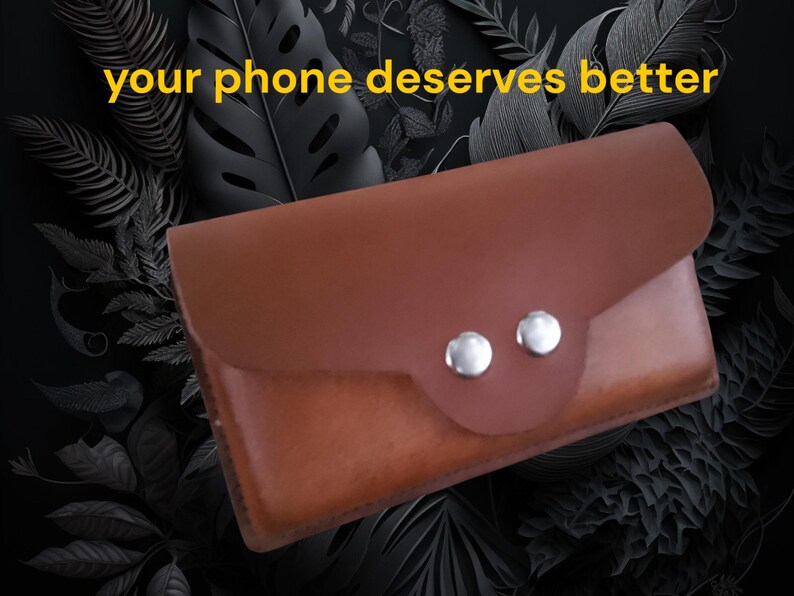 Peut inclure: Un &eacute;tui de t&eacute;l&eacute;phone en cuir marron avec une fermeture &agrave; rabat et deux boutons argent&eacute;s. Le texte "your phone deserves better" est affich&eacute; en jaune en haut. L'&eacute;tui est pos&eacute; sur un fond sombre avec des motifs de feuilles.