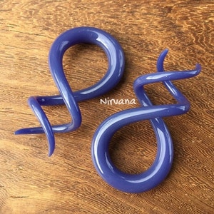 May include: A pair of purple glass ear gauges, one is a simple loop and the other is a spiral.