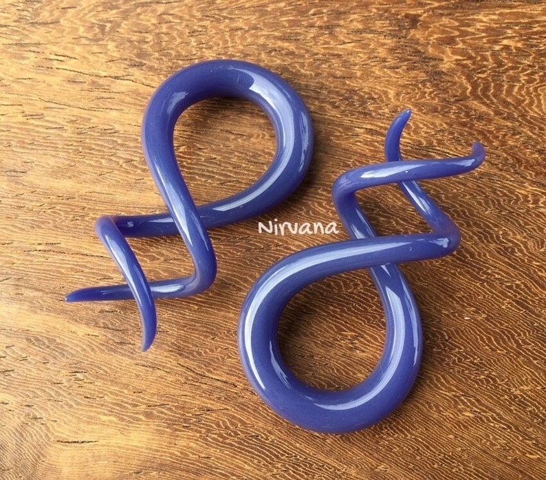 May include: A pair of purple glass ear gauges, one is a simple loop and the other is a spiral.