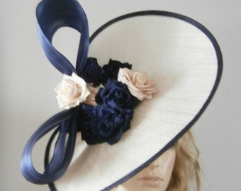 hand crafted almond sinamay twister edged in a navy trim embellished with silk flowers & bow