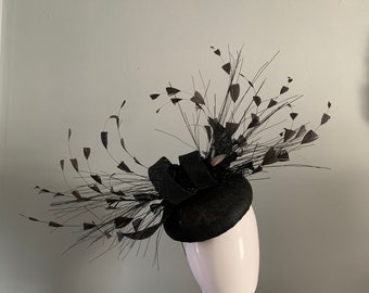 Zwarte barethoed-fascinator versierd met handgesneden veren en zijden bloemen.