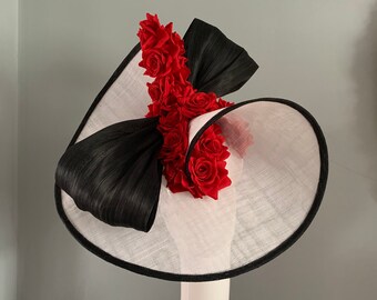 white twisting saucer edged in a black trim adorned with a black silk abaca sculptured bow and a spray of silken red roses.