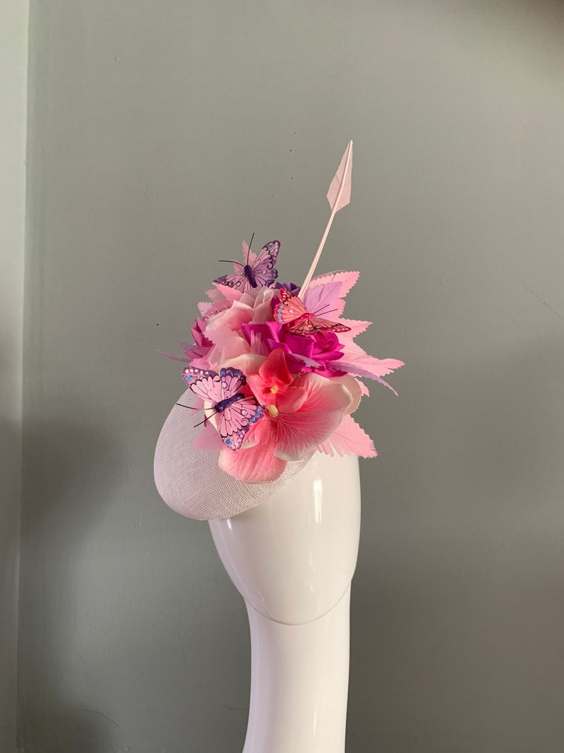White perching beret hat fascinator adorned with pale pink silken flowers feather butterflies,lilac and pink pastel feathers. image 1