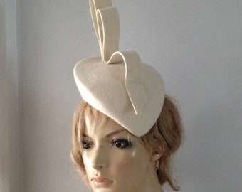 Ivory wool felt perching beret style hat adorned with sculptured loops.