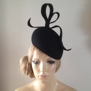 Black wool felt perching beret hat adorned with sculptured ribbon detail.