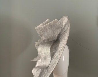 hand made bespoke metallic silver sinamay saucer hat with sculptured over sized bow detail.