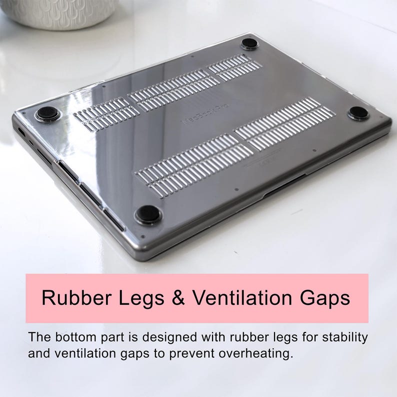 May include: A transparent, dark-tinted protective laptop hard shell case featuring four circular black rubber feet on the corners and multiple horizontal ventilation slots across the bottom panel to facilitate airflow and prevent overheating.