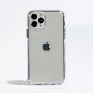 May include: A clear phone case with a silver iPhone inside. The phone has a black Apple logo and a camera lens with four black circles.