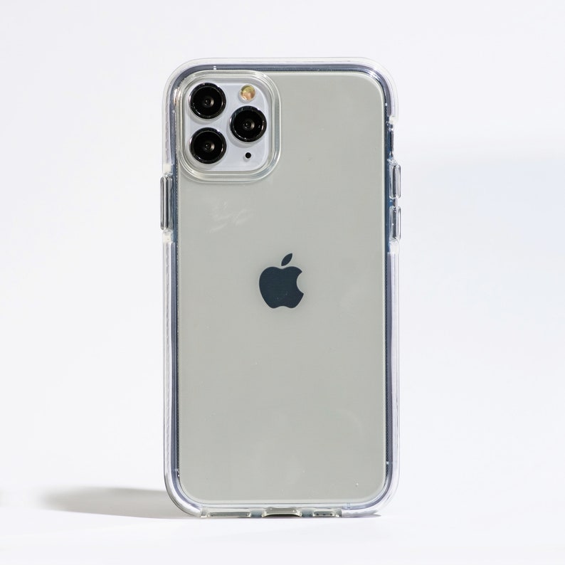 May include: A clear phone case with a silver iPhone inside. The phone has a black Apple logo and a camera lens with four black circles.