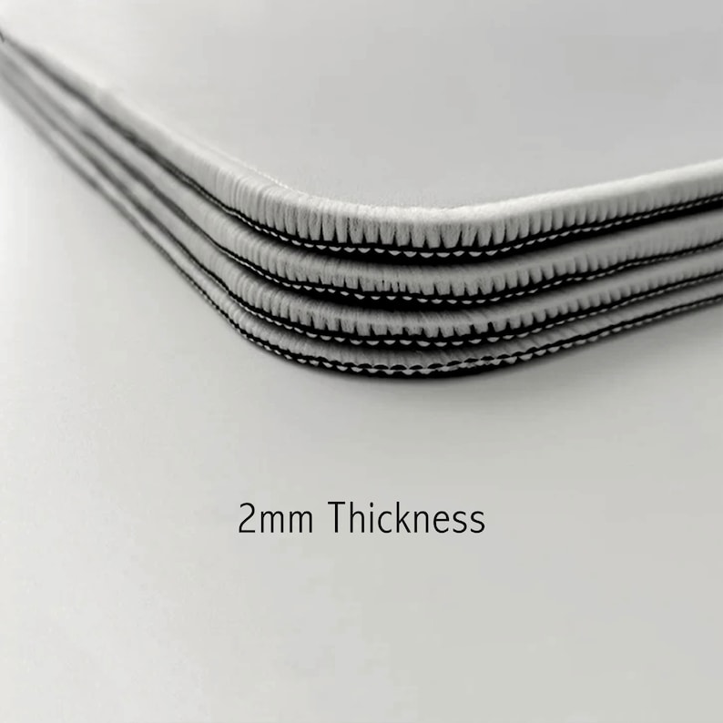 May include: Close-up of three layers of white fabric with black stitching around the edges. The fabric is 2mm thick.