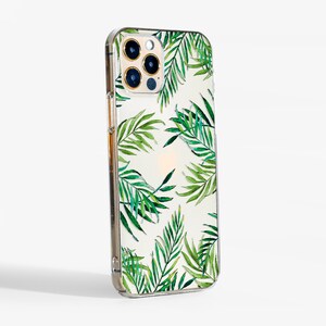 May include: Clear phone case with a tropical leaf pattern in shades of green on a white background. The case has a transparent border and a camera cutout.