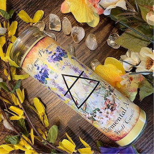 May include: A white candle with a yellow label that says "Elemental Air Spell Candle" and "Madame Phoenix's" in a floral design with a triangle symbol.
