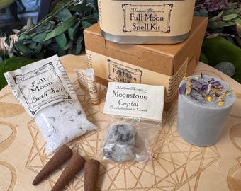 May include: A Madame Phoenix Full Moon Spell Kit containing a metal tin, a brown cardboard box, a bag of bath salt, a small vial, a moonstone crystal in a plastic bag, a grey pillar candle topped with dried flowers, and three brown incense cones.