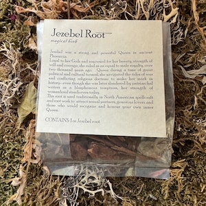 May include: A small, clear plastic bag containing brown, dried herbs labelled "Jezebel Root magical herb". The label includes a description of Jezebel, a powerful Queen in ancient Phoenicia, and the use of the root in North American spellcraft.