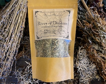 May include: A brown paper bag with a clear window showing a blend of dried herbs. The bag has a label that reads "River of Dreams, riviere des reves, Tea Blend/Melange de the, Madame Phoenix".