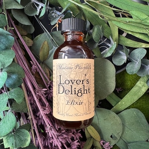 May include: A brown glass bottle with a black cap, labelled "Lovers Delight Elixir" by Madame Phoenix. The label features illustrations and text. The bottle is surrounded by green leaves and purple stems.